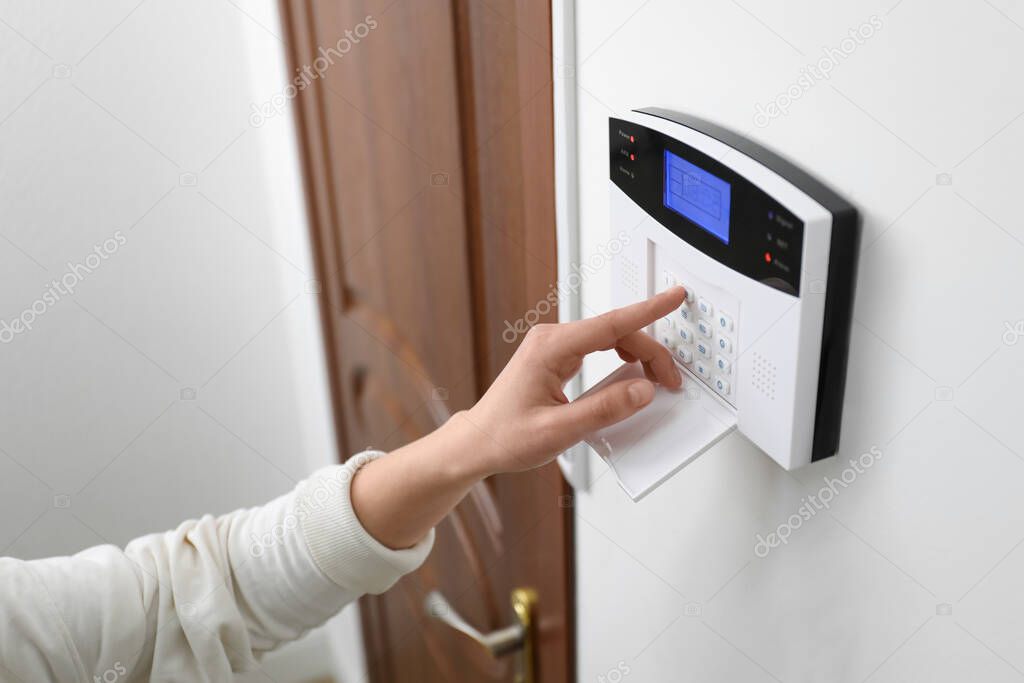 Woman entering code on home security system near door, closeup