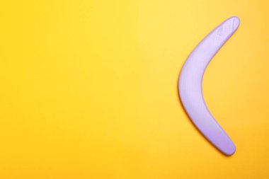 Sarı arka planda leylak rengi bumerang, üst manzara. Metin için boşluk