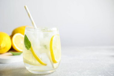 Açık gri masada bir bardak soğuk limonata, yakın plan. Metin için boşluk