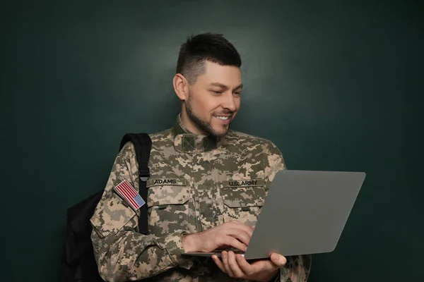 Cadet with backpack and laptop near chalkboard. Military education