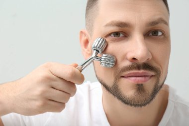 Hafif arka planda metal yüz silindiri kullanan bir adam. Yakın çekim