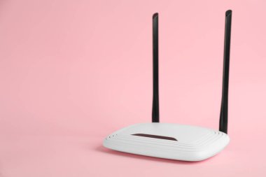 Açık pembe arka planda modern Wi-Fi yönlendirici. Metin için boşluk