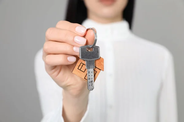 Makelaar Met Sleutel Tegen Grijze Achtergrond Close — Stockfoto