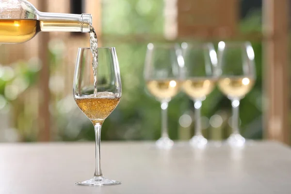 Versare Vino Bianco Dalla Bottiglia Bicchiere Sul Tavolo Contro Sfondo — Foto Stock