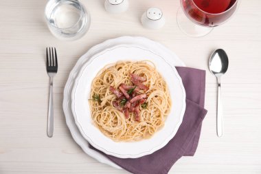 Lezzetli Carbonara makarnası beyaz ahşap masada servis edilir.
