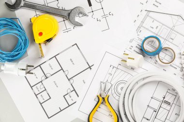 Elektrikçi aletleri ile düz kompozisyon ve masa üzerinde ev planı kağıtları