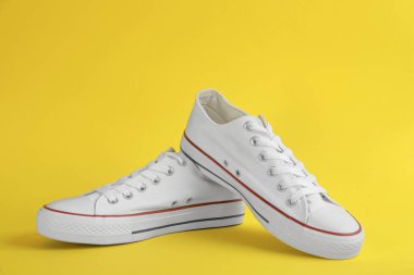 Sarı arka planda şık bir çift spor ayakkabı.