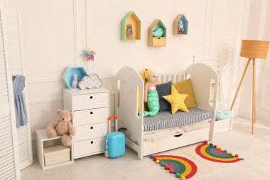 Bebek odasının içinde beşik ve oyuncaklar var.