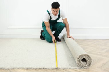 İçeriye yeni halı döşeyen mezuralı bir işçi