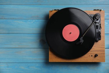 Mavi ahşap arka planda diski olan modern vinil plak çalar. Metin için boşluk