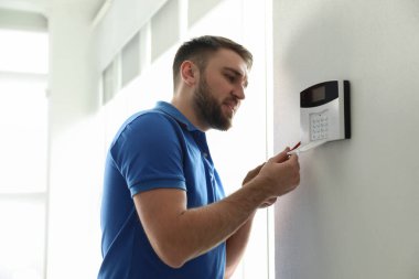 Beyaz duvarlara ev güvenlik sistemi kuran adam.