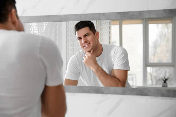 Hombre Guapo Tocando Cara Lisa Después Afeitarse Cerca Del Espejo — Foto de Stock