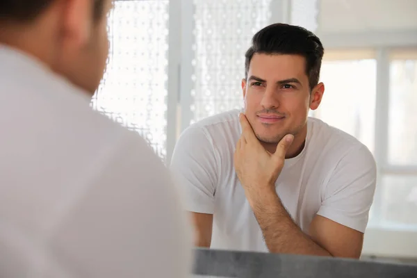 Bonito Homem Tocando Seu Rosto Liso Depois Barbear Perto Espelho — Fotografia de Stock