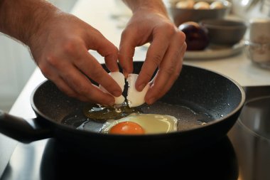 Adam tavada yumurta pişiriyor, yakın plan.