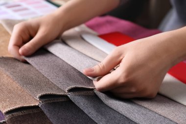 Farklı kumaş örnekleri arasından seçim yapan kadın, yakın plan.