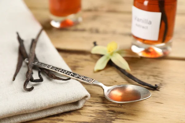 Aromatic vanilla extract and beans on wooden table
