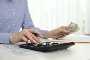 Masada hesap makinesiyle para sayan kadın, yakın plan.