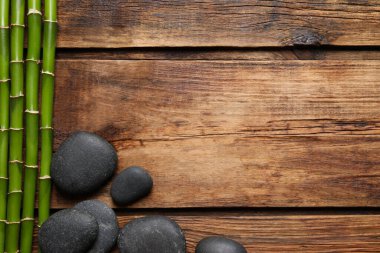 Tahta sehpanın üzerinde spa taşları ve bambu sapları var. Metin için boşluk