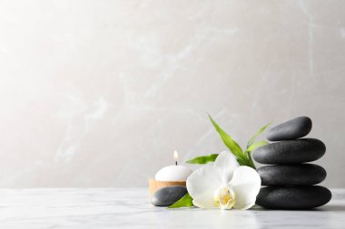 Spa taşları, bambu filizi, yanan mum ve beyaz mermer masada güzel orkide çiçeği, yazı için yer
