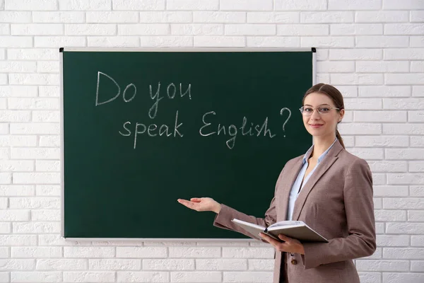绿色黑板旁边有题词的老师你会说英语吗 在课堂上 — 图库照片