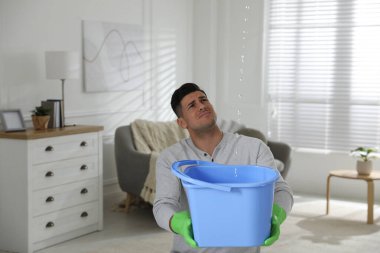 Duygusal adam oturma odasının tavanından su sızdırıyor. Hasarlı çatı