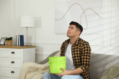 Duygusal adam oturma odasının tavanından su sızdırıyor. Hasarlı çatı