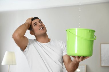 Duygusal adam oturma odasının tavanından su sızdırıyor. Hasarlı çatı