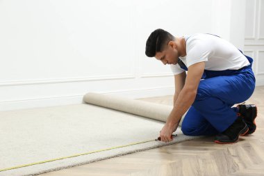 İçeriye yeni halı döşeyen mezuralı bir işçi