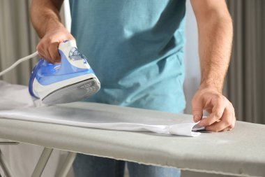 Evde temiz gömlek ütüleyen adam, yakın plan.