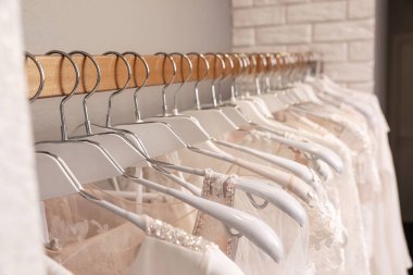 Butikte askılarda farklı gelinlikler, yakın plan.