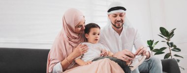 Mutlu Müslüman aile evdeki kanepede birlikte vakit geçiriyor. Pankart tasarımı 