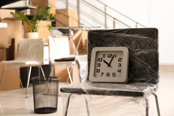 Packed chair and clock in office. Moving day