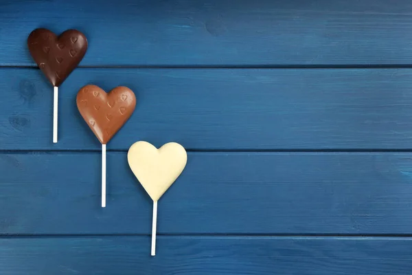 Farklı Çikolata Kalp Şekilli Lolipoplar Mavi Ahşap Masada Düz Yerde — Stok fotoğraf