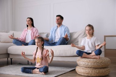 Aile oturma odasında rahat bir kanepeyle meditasyon yapıyor.