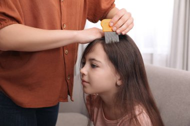 Anne, içeride kızının saçını bit tarağı ile tarıyor. Bit önleyici tedavi
