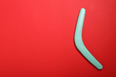 Kırmızı arka planda turkuaz ahşap bumerang, üst manzara. Metin için boşluk