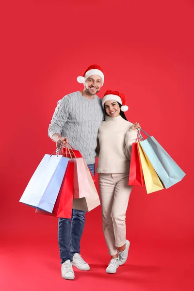 Joyeux Couple Avec Des Sacs Papier Sur Fond Rouge Shopping — Photo