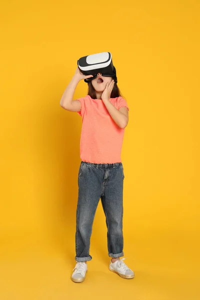 在黄色背景下使用虚拟现实耳机的情绪化小女孩 — 图库照片