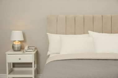 Otel odasındaki komodinin üzerinde rahat bir yatak ve lamba.