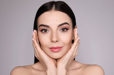 Gri arka planda siyah göz kalemi olan güzel bir kadın.