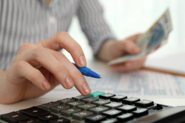 Masada hesap makinesiyle para sayan kadın, yakın plan.