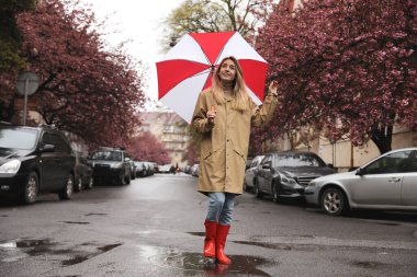 Bahar gününde şemsiyeli genç bir kadın yürüyor.