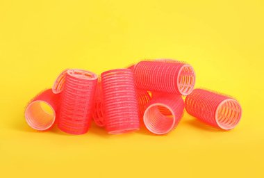 Sarı arka planda bir sürü kızıl saç bigudisi var.