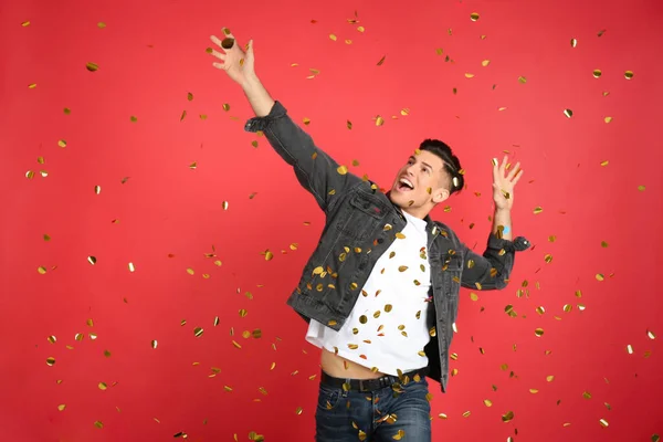 Emotional man and falling confetti on red background