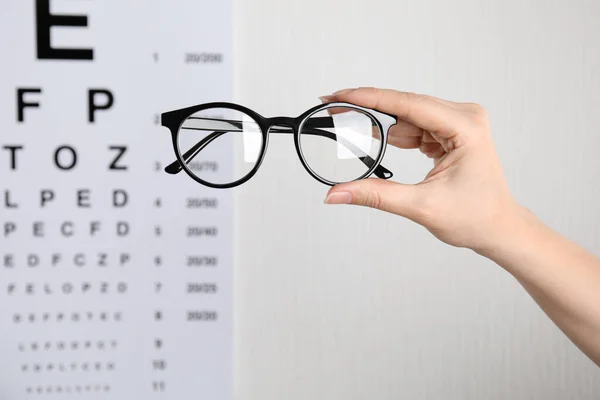 女人拿着眼镜与眼表对视 背景浅 眼科医生处方 — 图库照片