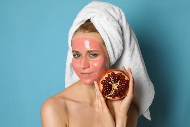 Nar maskeli genç bir kadın ve açık mavi arka planda taze meyve.