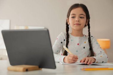 Küçük kız evde modern tabletle ödev yapıyor.