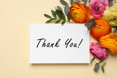 Güzel Ranunculus çiçekleri ve mesajlı tebrik kartı bej arka plan, düz uzanma teşekkür ederim 