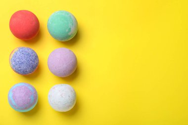 Sarı arka planda renkli banyo bombaları, düz yatış. Metin için boşluk