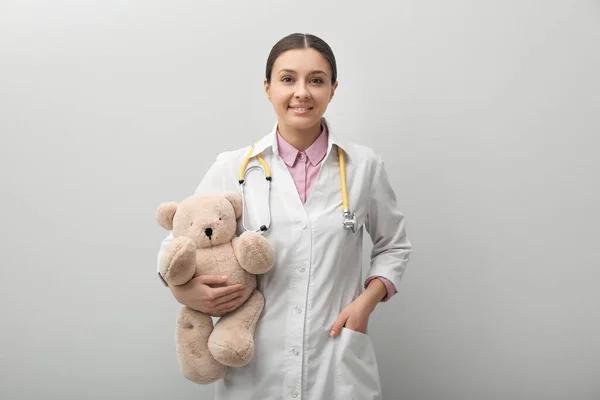 带泰迪熊的儿科医生和浅灰背景的听诊器 — 图库照片